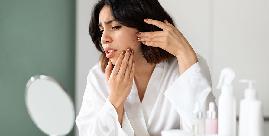 Unhappy woman examining skin concern in mirror
